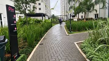 A pathway leading to a residential building with a signboard on the left.