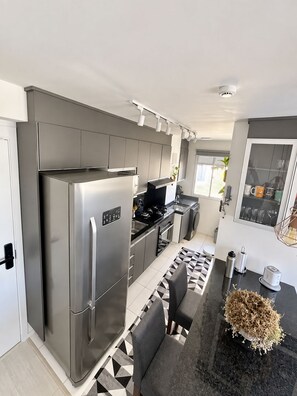 Una cocina moderna con un refrigerador de acero inoxidable, una encimera negra y un tapete estampado.