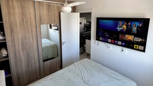 Quarto com cama, guarda-roupa e televisão na parede.