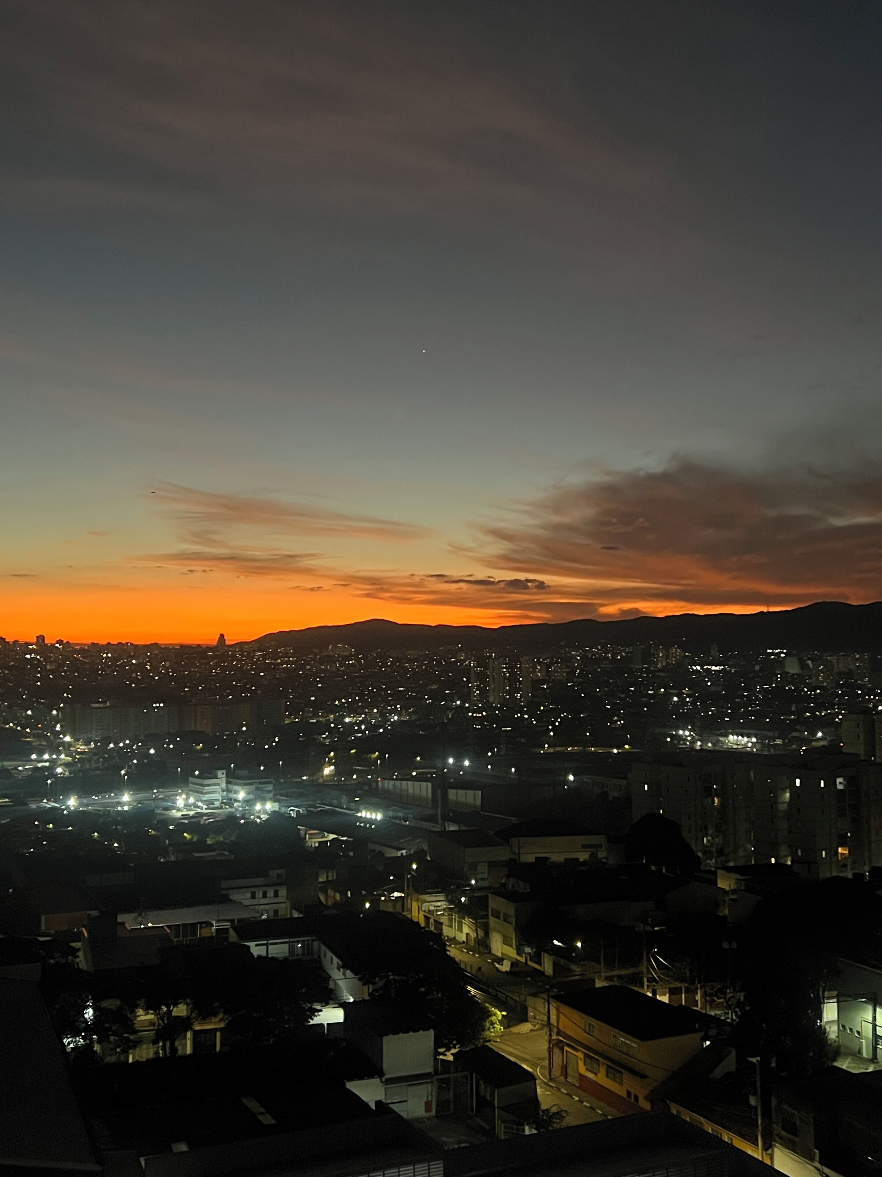 A cityscape at dusk with buildings and lights.