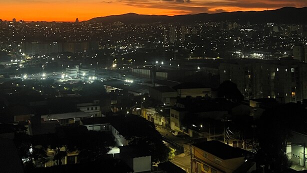 Paisagem urbana ao entardecer, com edifícios e luzes.