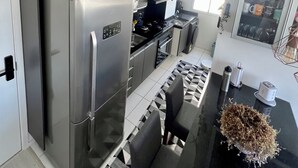 Uma cozinha moderna com eletrodomésticos de aço inoxidável, bancada preta e piso com padrão geométrico.