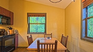 A kitchen with a dining table, chairs, and a window with a view of trees. - Wisconsin Dells | Pool & Waterpark Access | 2BR Cottage (Wisconsin Dells)
