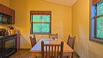 A kitchen with a dining table, chairs, and a window with a view of trees.