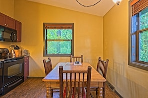 A kitchen with a dining table, chairs, and a window with a view of trees. - Wisconsin Dells | Pool & Waterpark Access | 2BR Cottage (Wisconsin Dells)