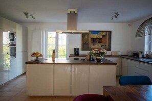 A modern kitchen with a central island, a microwave, and a dining area with a table and chairs. - at the Johanneshof winery (Minheim)