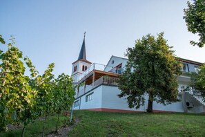 A building with a prominent tower, a balcony, and a tree in the foreground. - at the Johanneshof winery (Minheim)