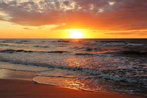 Un coucher de soleil sur l’océan, avec des vagues qui se rapprochent du rivage.