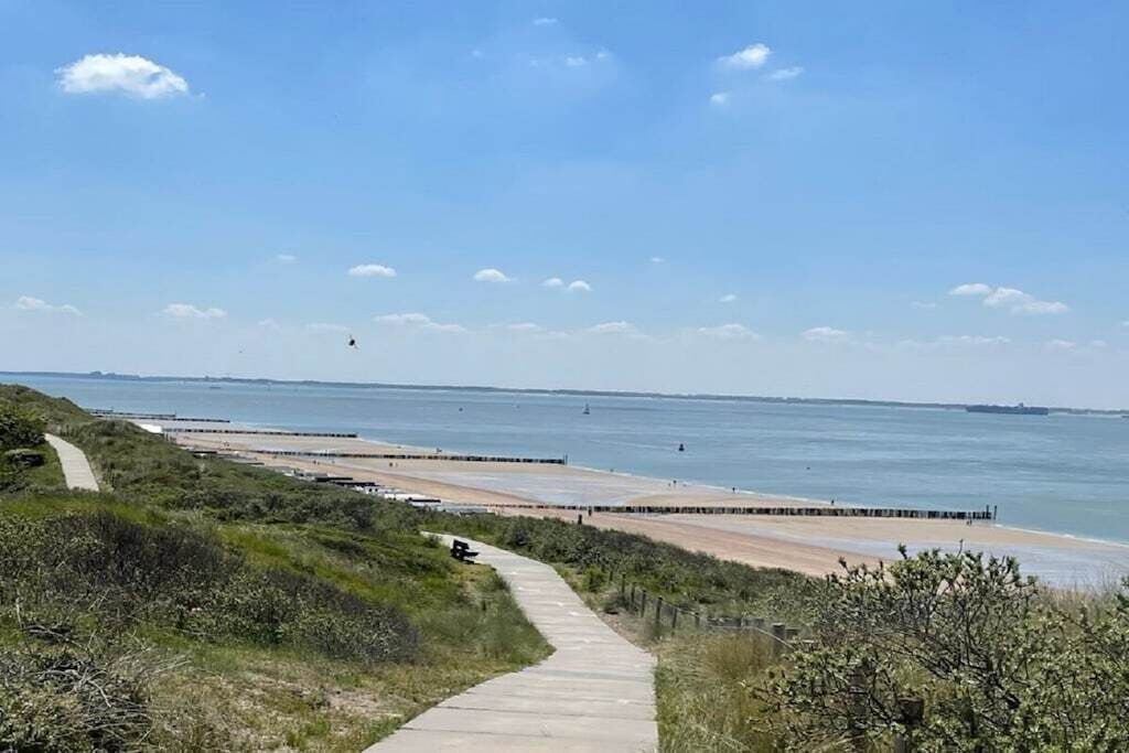Een kustpad dat naar een strand leidt, met een heldere lucht.
