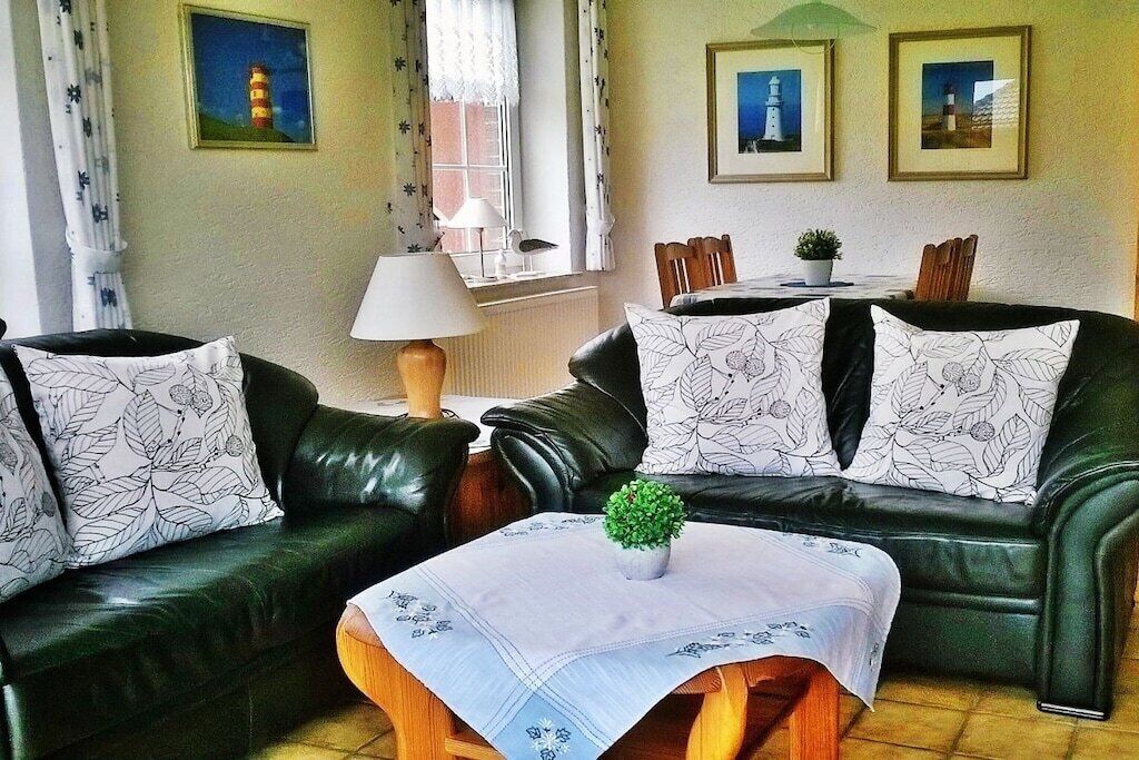 A living room with a sofa, a table with a plant, and framed pictures on the wall.