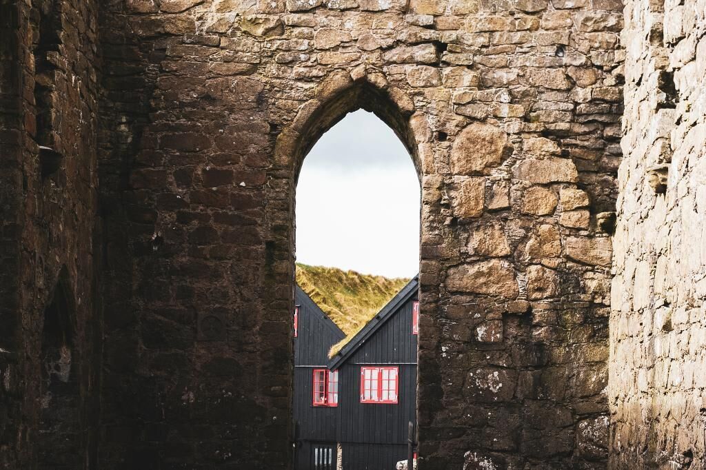 A stone archway with a building visible through it.