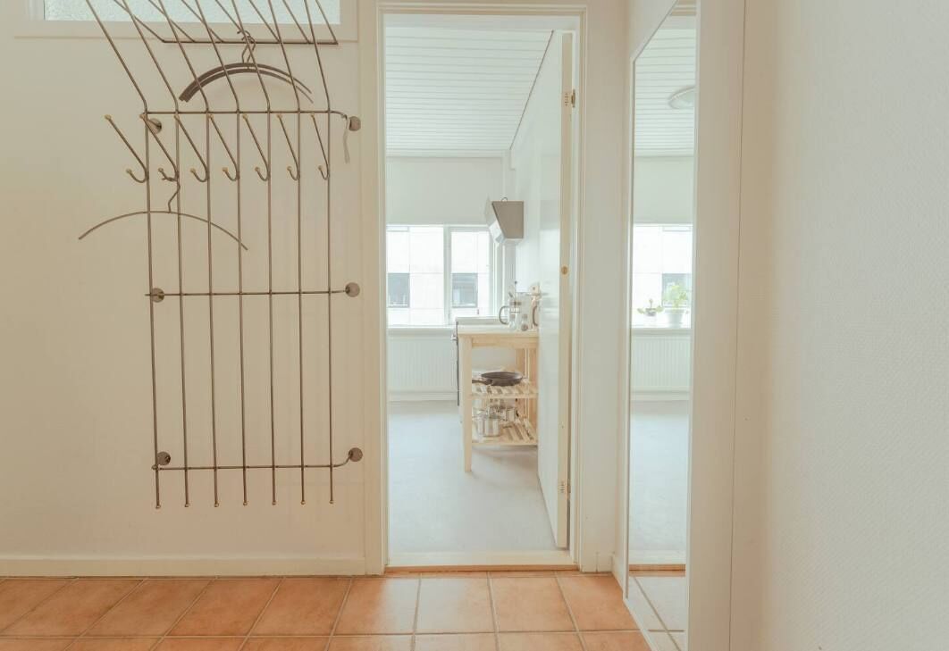 A room with a door leading to a kitchen area.
