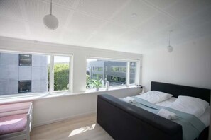 Makuuhuoneessa on sänky, kaksi ikkunaa, penkki ja kattovalaisin.
