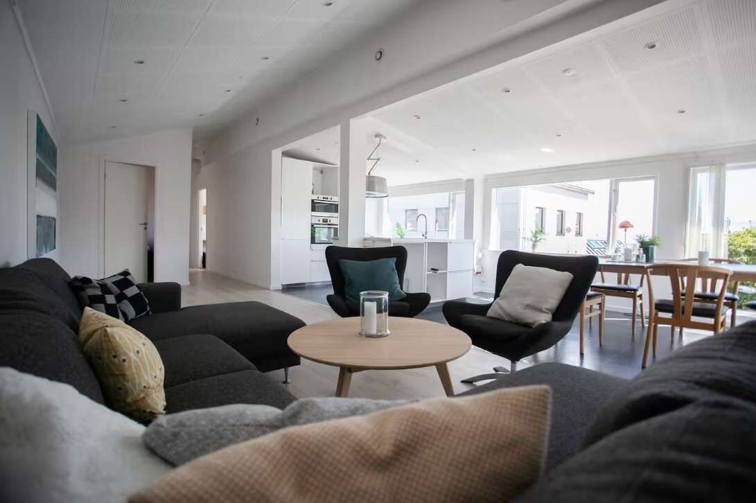 Una sala moderna con un sofá, sillones y una mesa de centro.