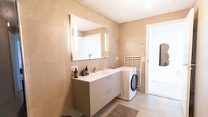Et stilfuldt badeværelse med et stort spejl, en indbygget vaskemaskine og toilet.