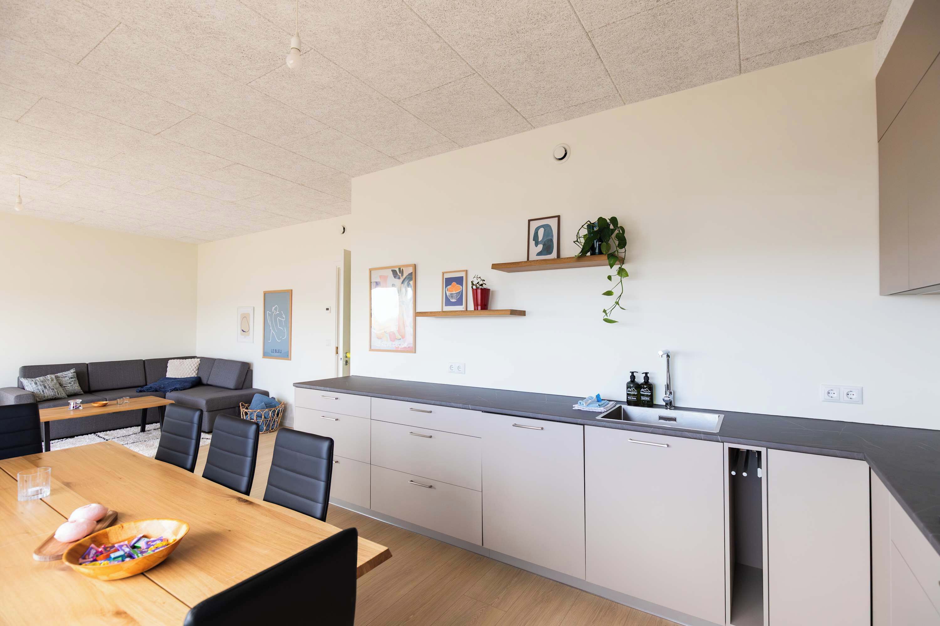 Eine moderne Küche mit Essbereich, ausgestattet mit einem Holztisch, Stühlen und einer Couch.