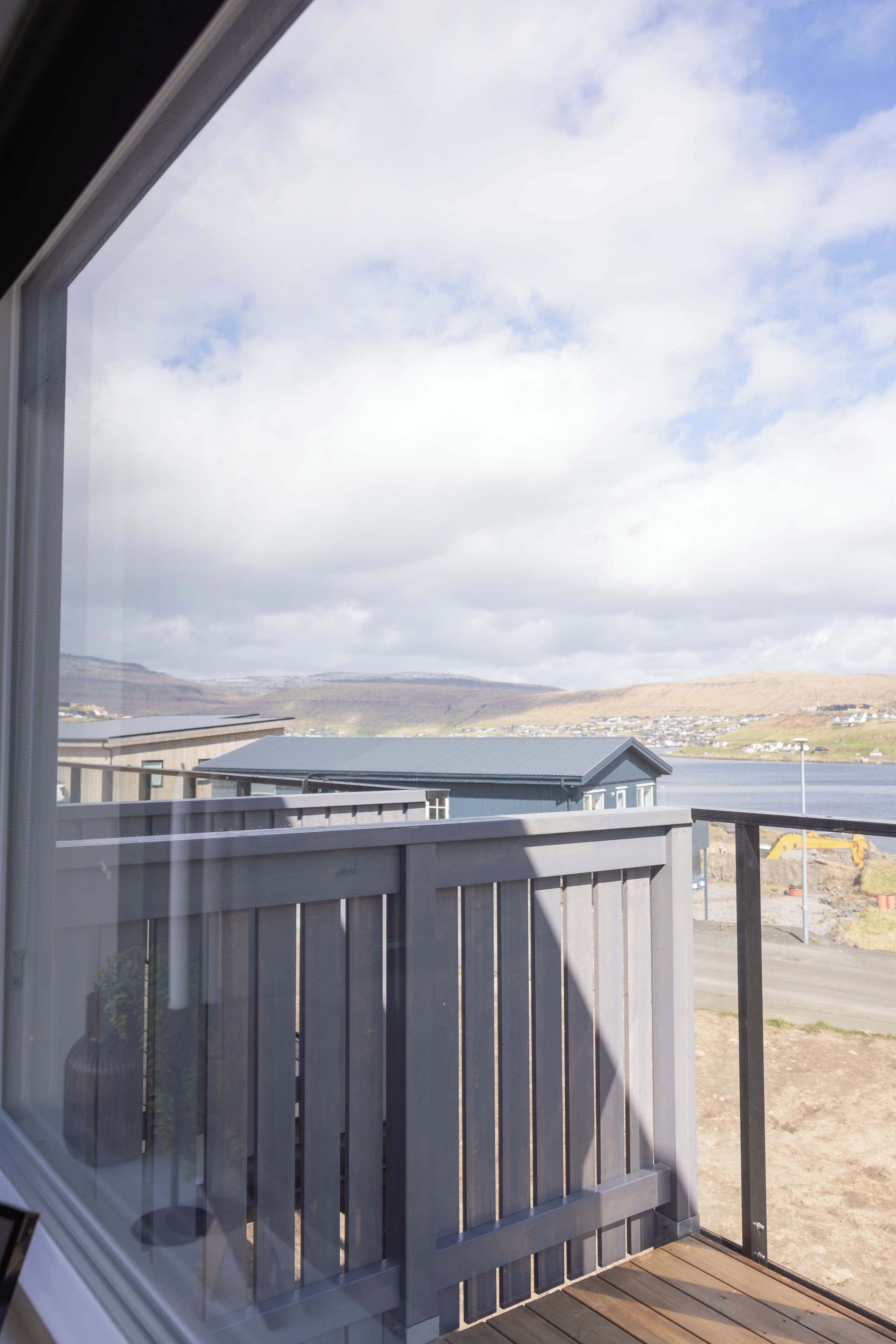 A balcony with a view of a distant landscape, including a body of water and a town.