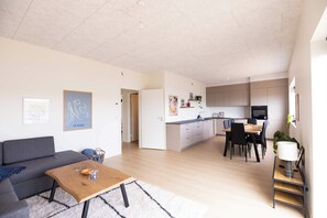 A modern apartment with a living room, dining area, and kitchen.