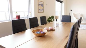 Une salle de conférence avec une longue table, des chaises noires, un saladier en bois rempli de collations et un tableau accroché au mur.