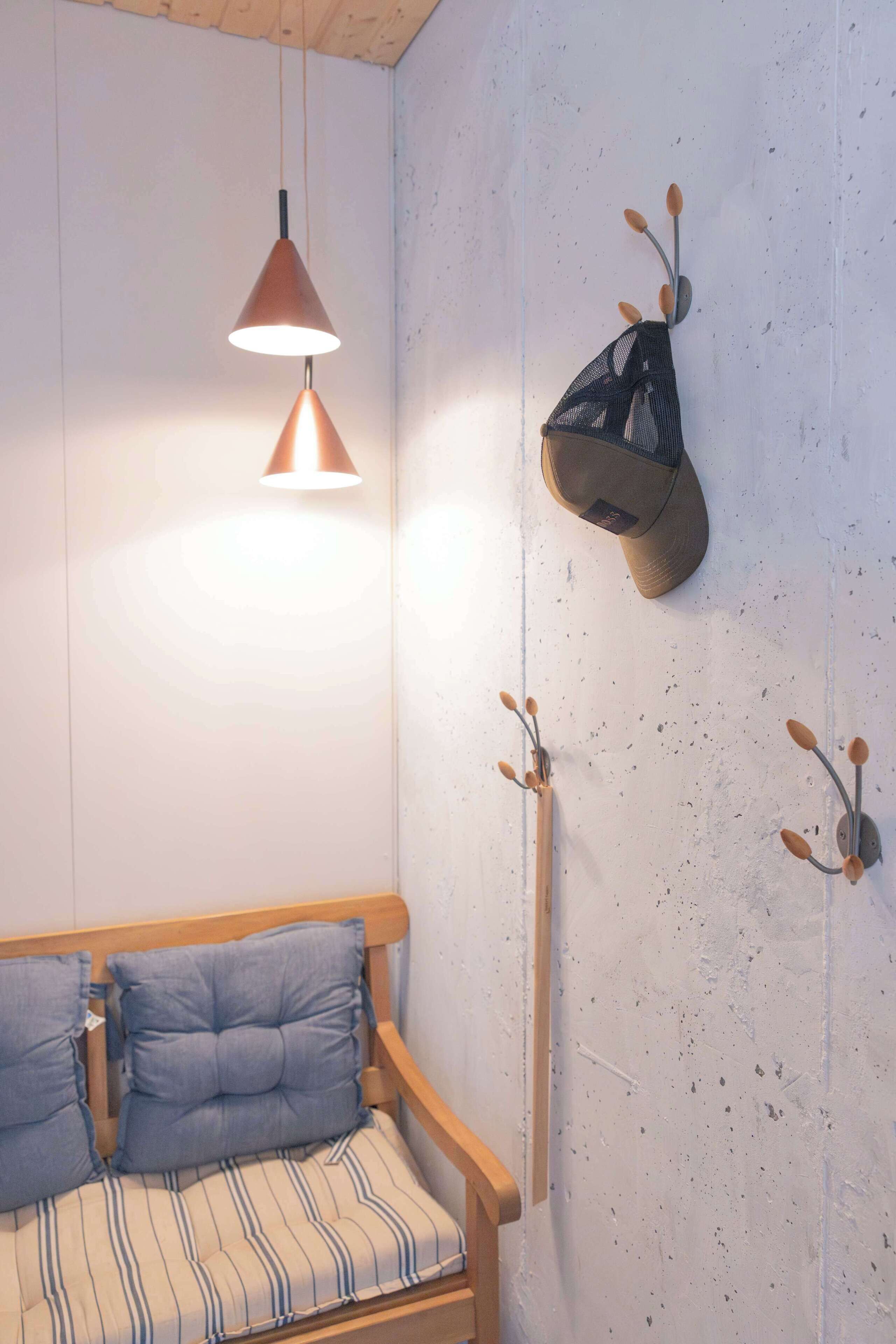 Une pièce avec un banc en bois, une lampe suspendue et des crochets fixés au mur.
