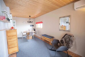A compact living space with a kitchenette, a dining area, a seating area with a bench, and a large mirror. - Scenic Villa Cabin by the Sea in Faroe Islands (Innan Glyvur)