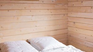 Una habitación con paneles de madera, una cama con ropa de cama blanca y dos cuadros en un estante.