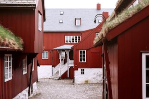 A narrow cobblestone alley between red buildings with white walls and a staircase leading to a second floor. - Cozy & Characterful Faroese Apartment - 2 Bedrooms (Tórshavn)
