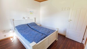 Une chambre avec un lit simple, un plafond en bois et une porte blanche.