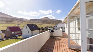 A wooden deck with a view of a rural landscape and mountains.