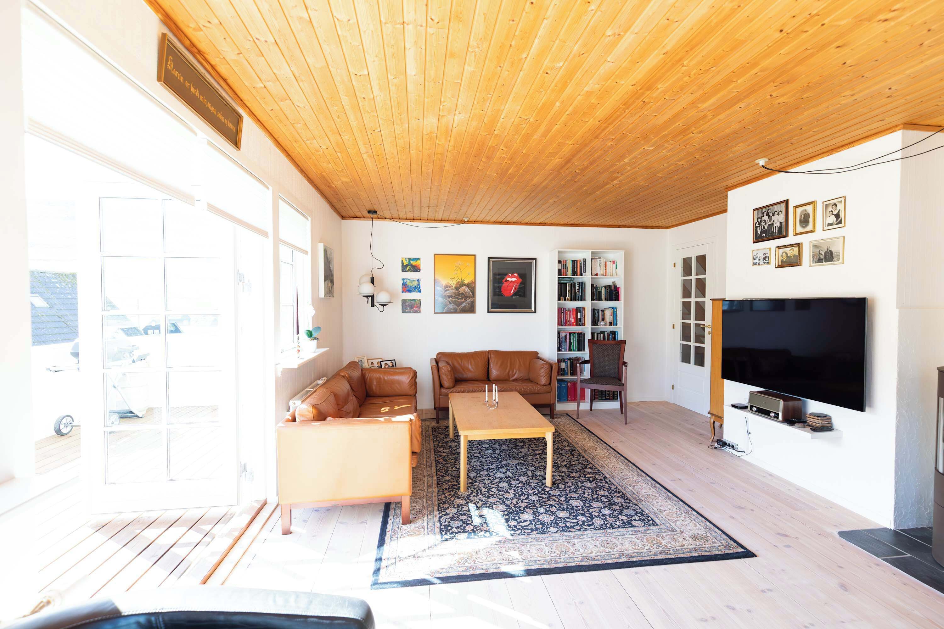 Un soggiorno con soffitto in legno, un divano, un tavolino, una libreria e una televisione.