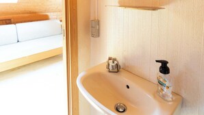 A wooden interior with a white sink, a mirror, and a bottle of hand sanitizer.
