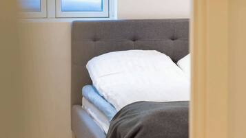 A bedroom with a bed, a window, and a wooden floor.