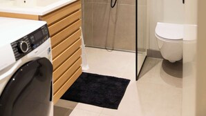 Een moderne badkamer met douche, toilet en wastafel.