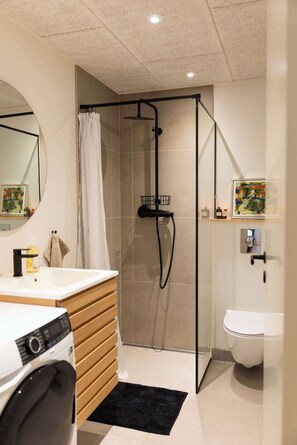 A modern bathroom with a shower, toilet, and sink. - Stylish 2BR Apartment in Peaceful Hoyvik (Hoyvík)