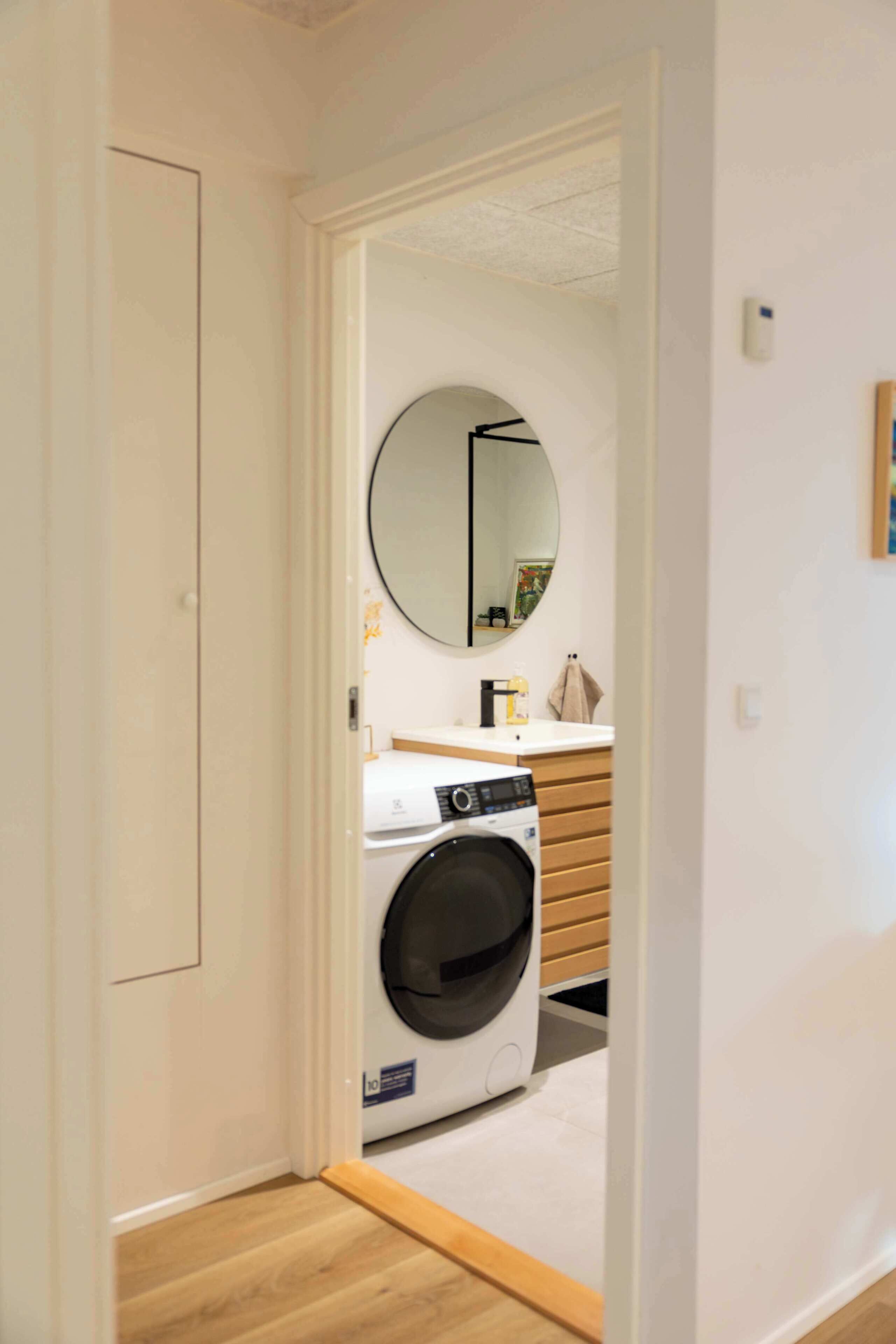 Une buanderie équipée d’un lave-linge, d’un sèche-linge et d’un miroir fixé au mur.