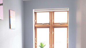 A bedroom with a bed, a window, a bedside table, and a potted plant. - A serene escape in scenic surroundings (Streymnes)