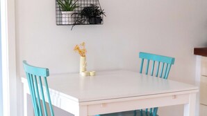 A dining table with four chairs, a small plant, and a wall-mounted light switch. - A serene escape in scenic surroundings (Streymnes)