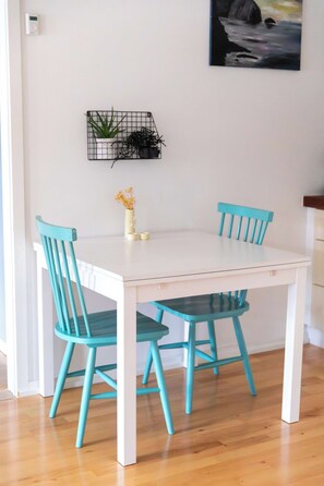 Een eettafel met vier stoelen, een kleine plant en een lichtschakelaar aan de muur.