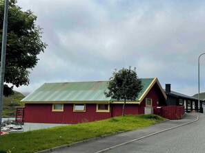 Een rood gebouw met een groen dak, een klein raam en een deur.