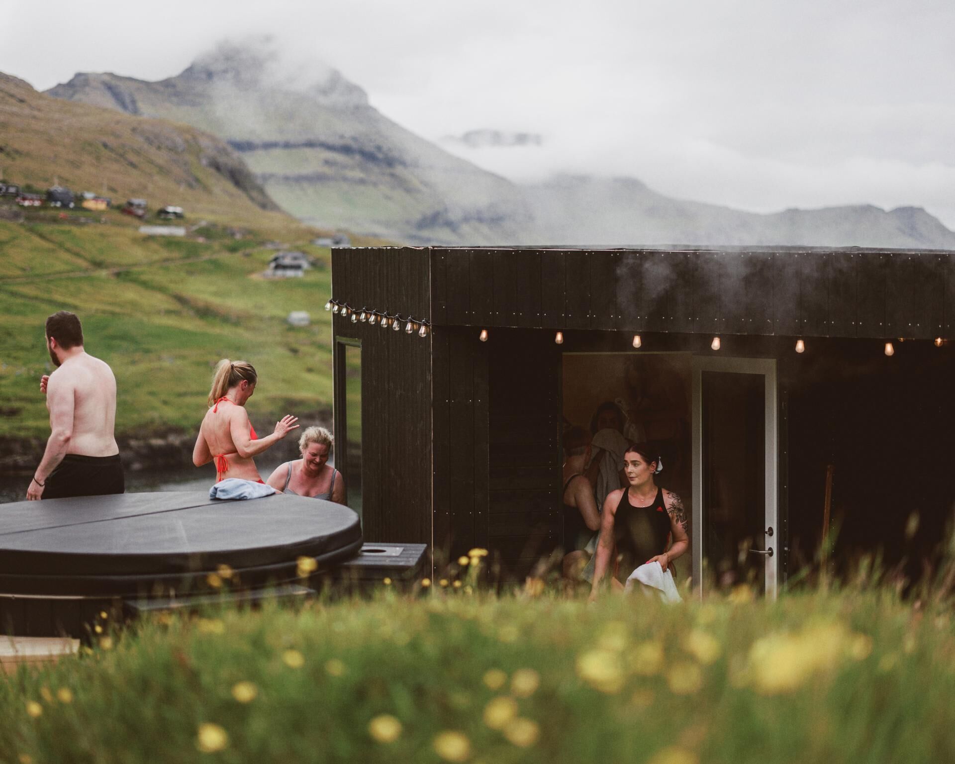 A rustic outdoor setting with a stage and seating area, surrounded by greenery and mountains.