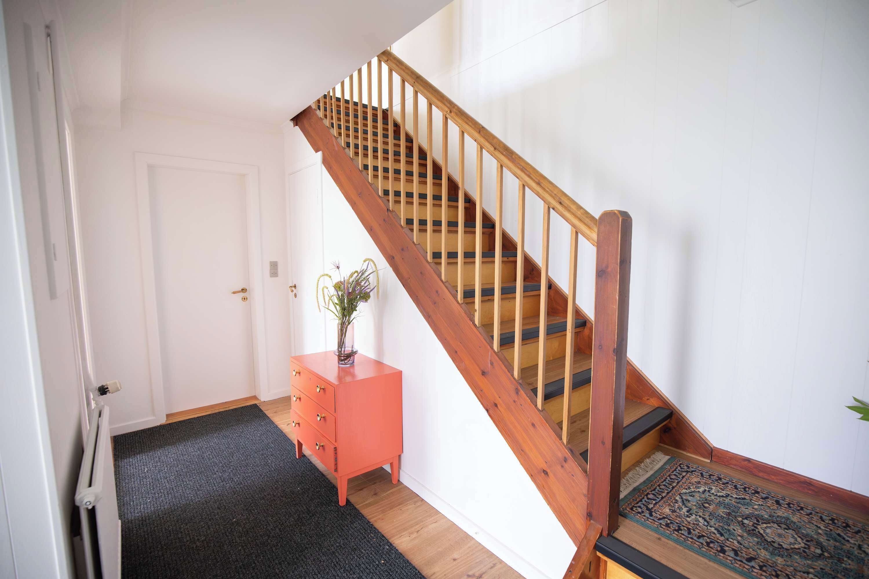 Un escalier avec des rampes en bois et un revêtement de sol en moquette menant à une porte.
