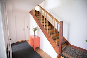 Una escalera con barandillas de madera y piso alfombrado que conduce a una puerta.