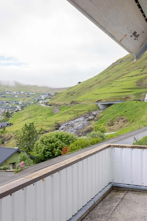 A view from a balcony overlooking a green hillside with a small village below.