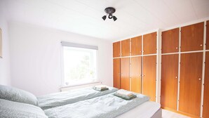 Quarto com cama, janela e guarda-roupa.
