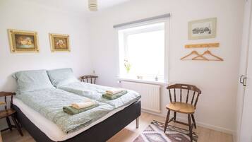 Een slaapkamer met een bed, een stoel, een raam en spullen aan de muur.