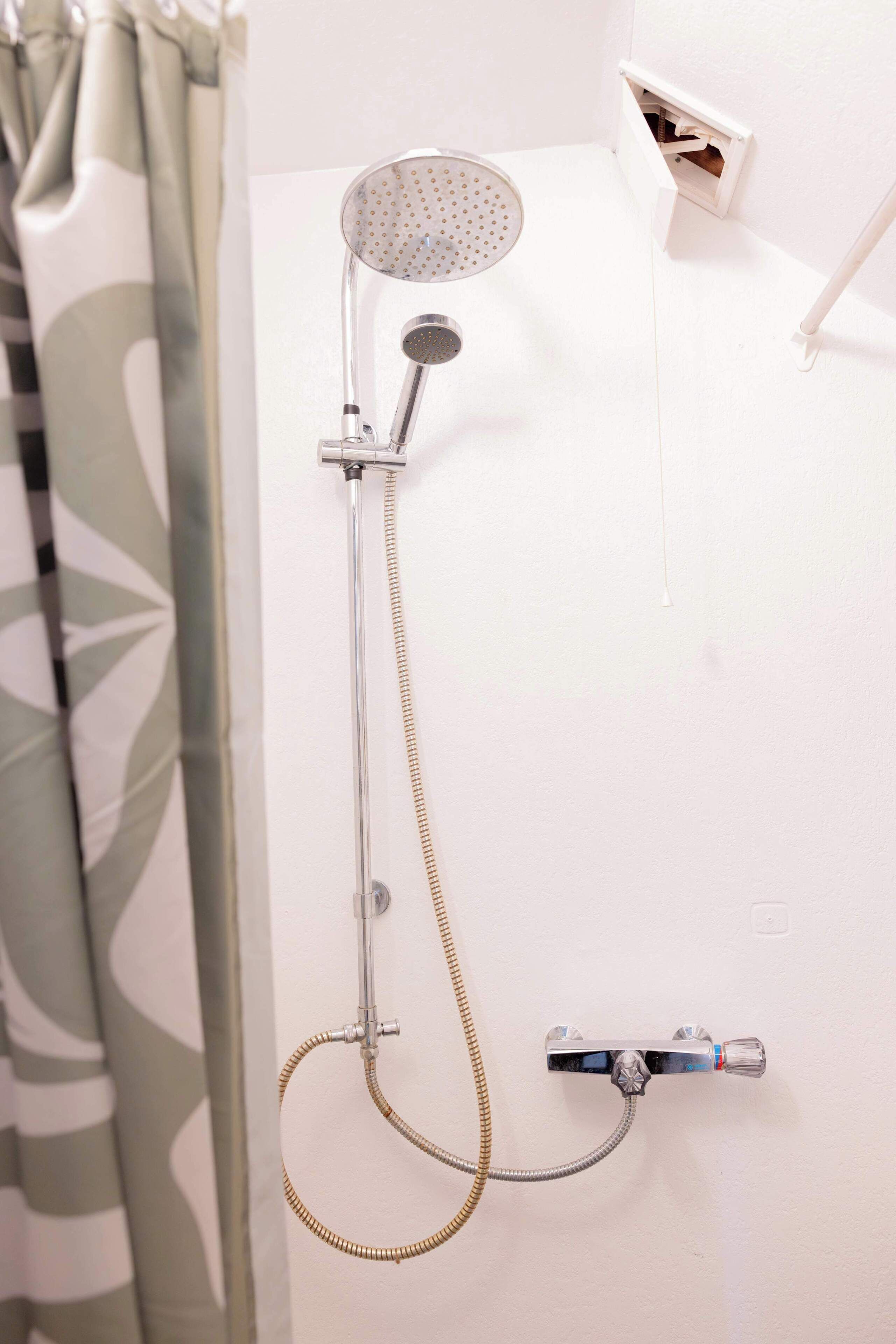 Eine Dusche mit Handbrause und Duschwandhalterung.