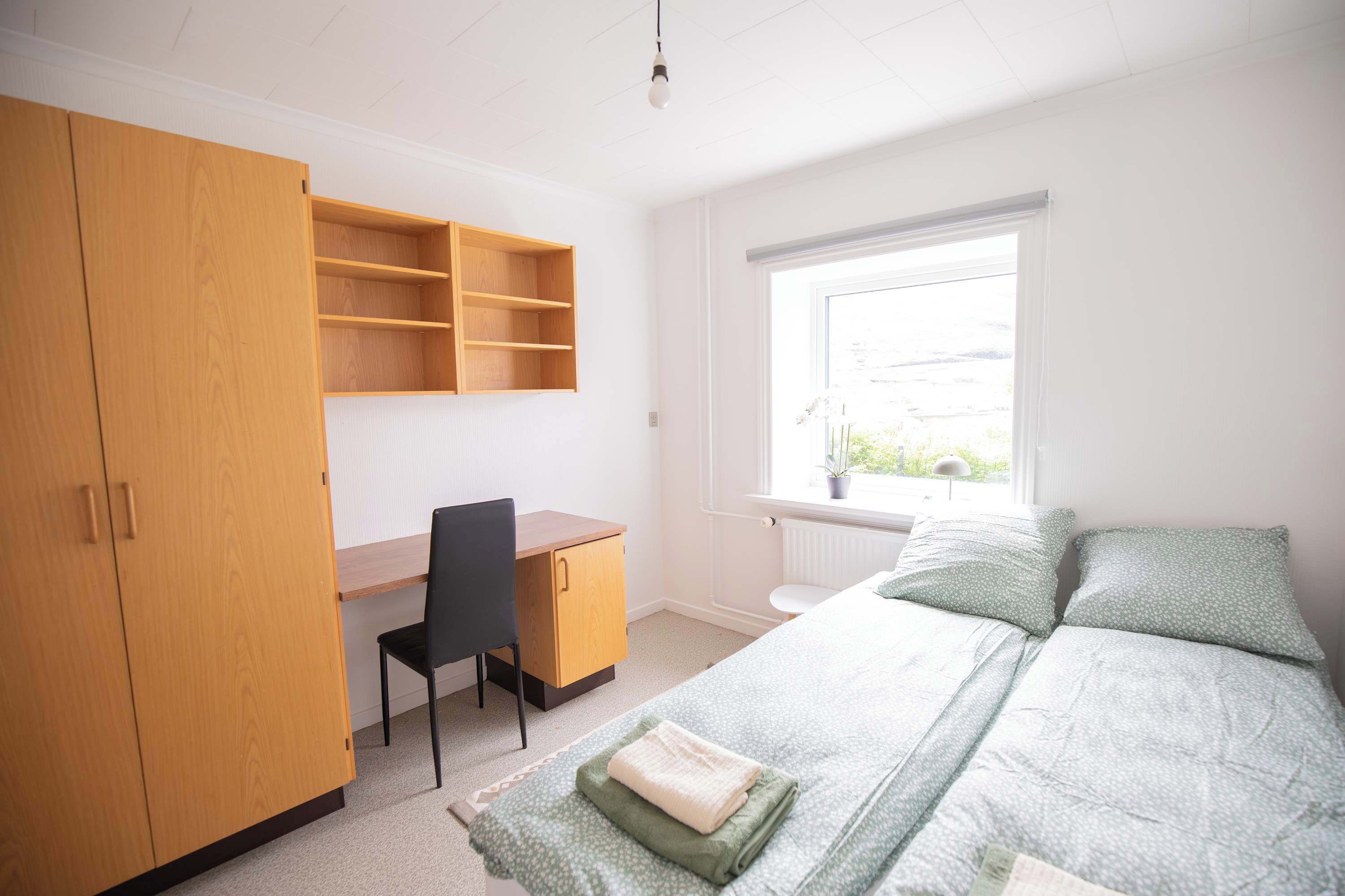 Un dormitorio con cama, escritorio, silla y armario.