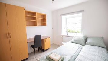 Un dormitorio con cama, escritorio, silla y armario.