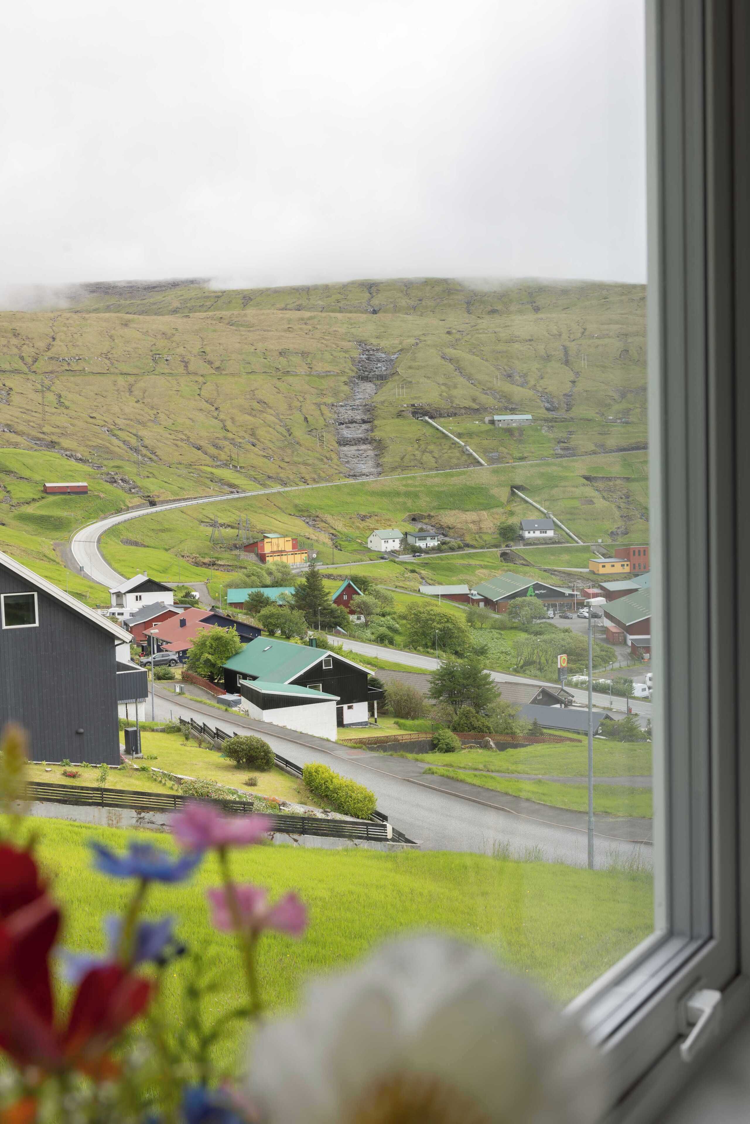 Un paysage rural avec une route sinueuse, des maisons et une grande structure industrielle.