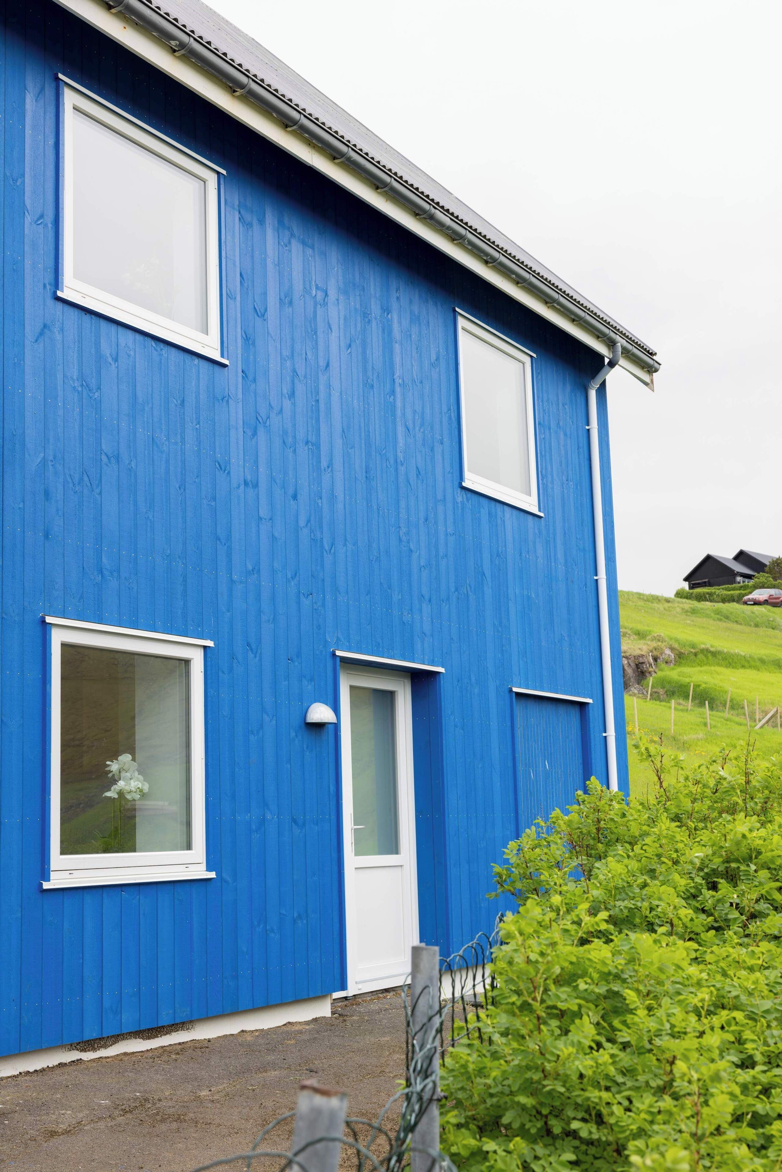 Un bâtiment bleu avec des fenêtres à encadrement blanc et une porte.